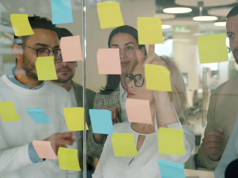 Team brainstorming with sticky notes on a glass wall