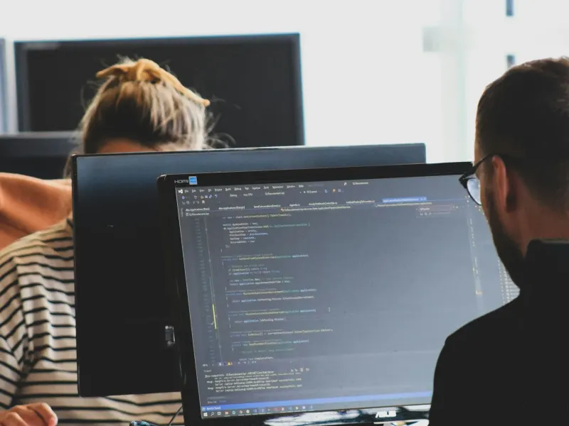 Two developers pair-programming at their monitors