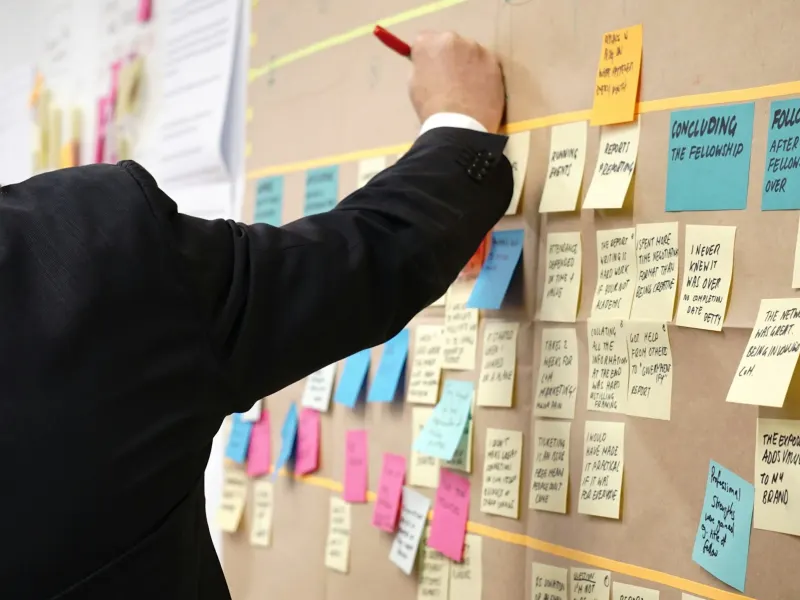Consultant mapping ideas on a wall of sticky notes during a strategy workshop